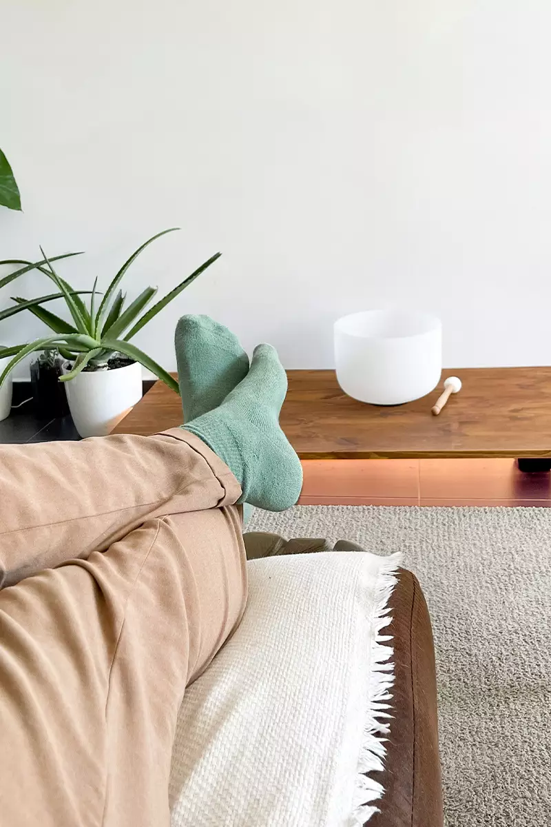 femme relaxant sur un canapé avec un bol tibétain sur la table